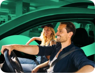 Two people smiling as they drive into a parking spot
