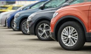 Row of rental cars parked outside a car rental office, ready for pickup