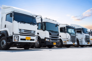 Row of white commercial trucks parked in a spacious outdoor lot under a clear sky