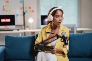 Woman recording a podcast or video with headphones and microphone in a home studio