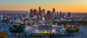 Aerial view of Dodger Stadium with downtown Los Angeles skyline at sunset on game day
